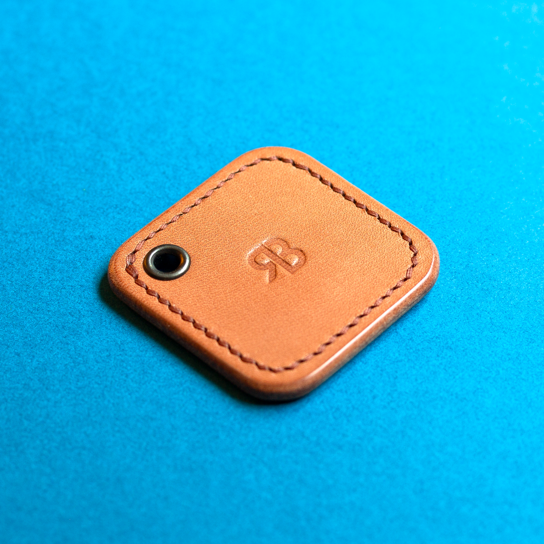 Leather hand-stitched NFC key fob with a brand logo on a blue background