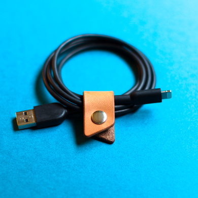 Black USB cable with a leather wrap and metal connector on a blue background