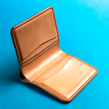 Load image into Gallery viewer, Full-grain hand-stitched brown leather wallet on a blue background, inside