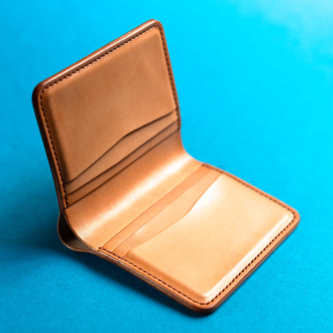 Full-grain hand-stitched brown leather wallet on a blue background, inside