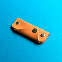 Load image into Gallery viewer, Full-grain brown leather key holder on a blue background