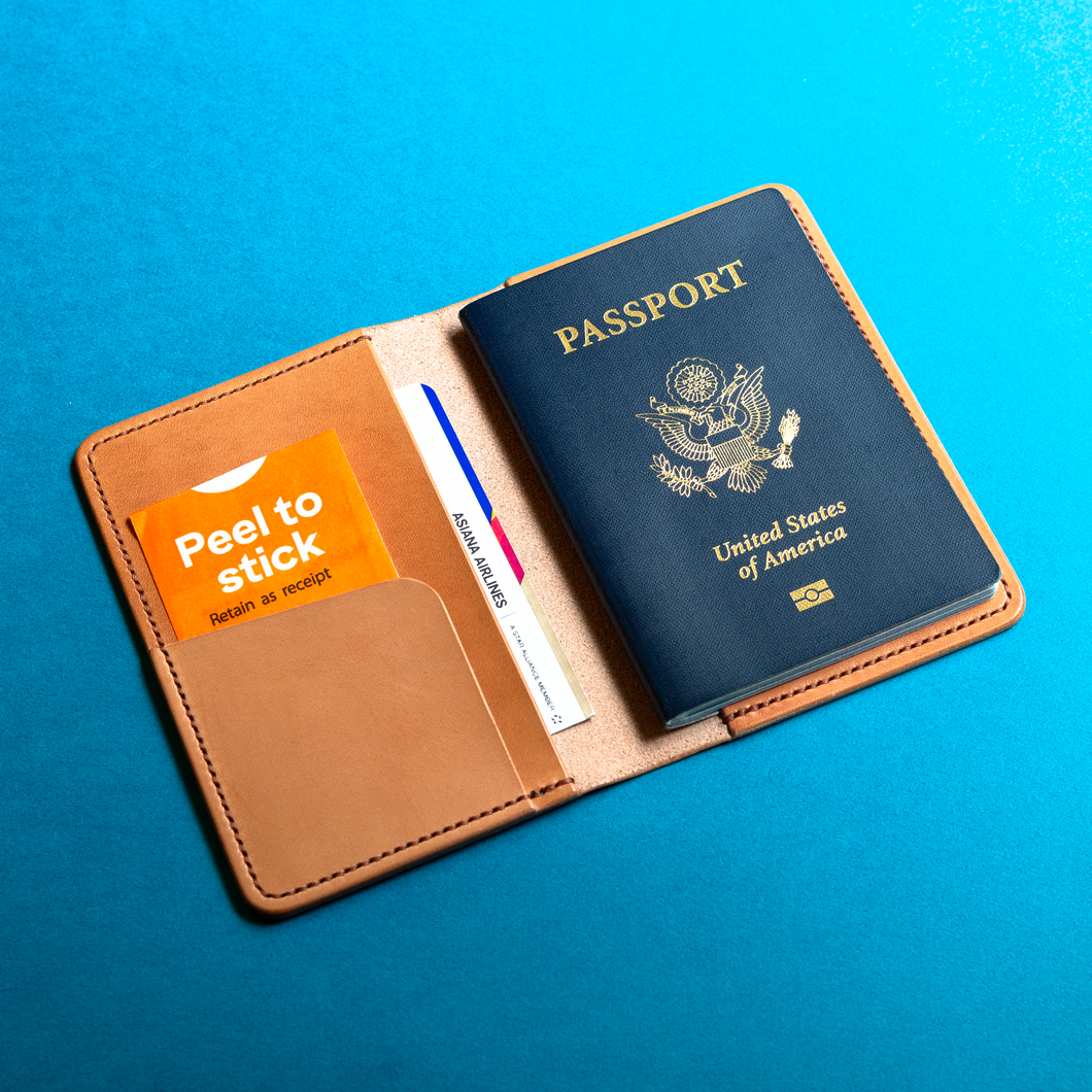 Full-grain hand-stitched brown leather passport holder with a United States passport on a blue background, inside